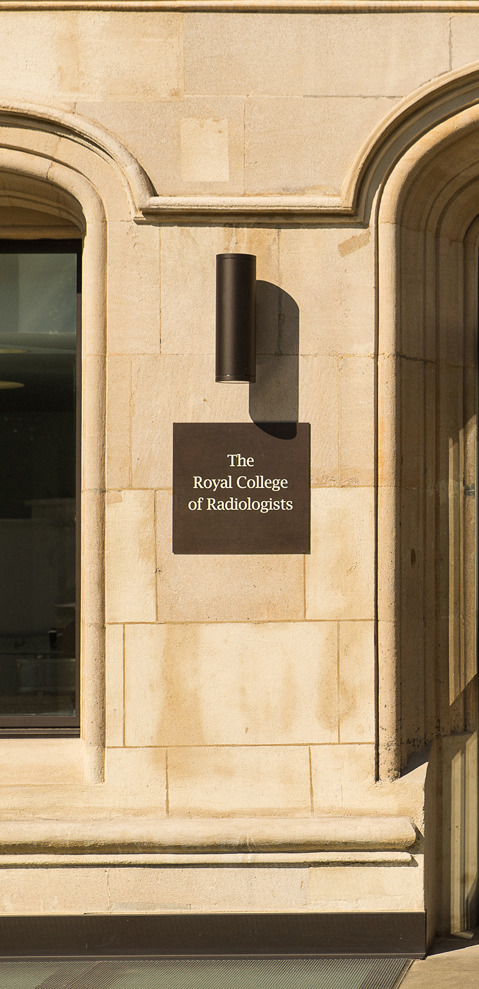 The open main entrance doors to a sandstone building next to a sign naming it as the Royal College of Radiologists. 